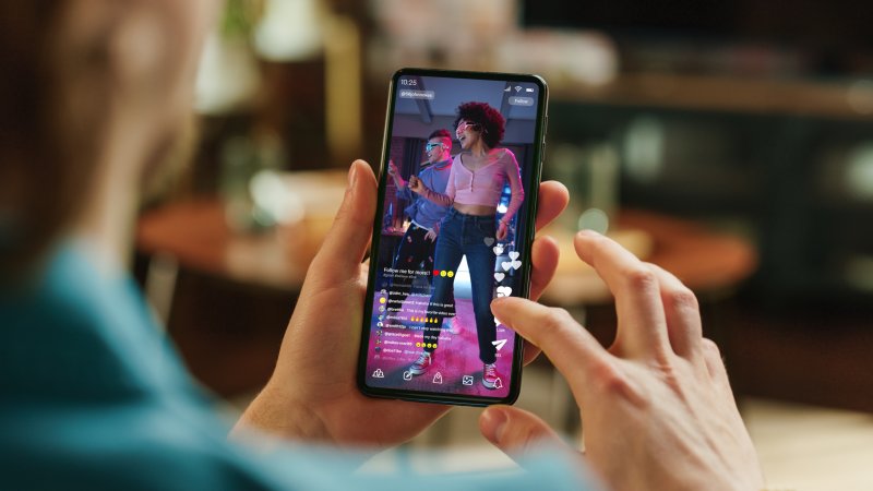 Creator watching a TikTok video on phone showing vibrant dance content